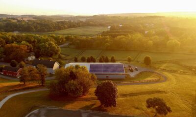 Sunset on a rural landscape that centers a barn with solar panels on the roof.