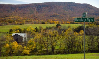 Rural fall landscape with mountains in the background and a road sign that says Mountain Valley in the foreground.