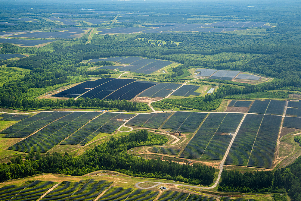 An areal image looking down at many fields of solar planned on mostly bare earth otherwise surrounded by farmland.