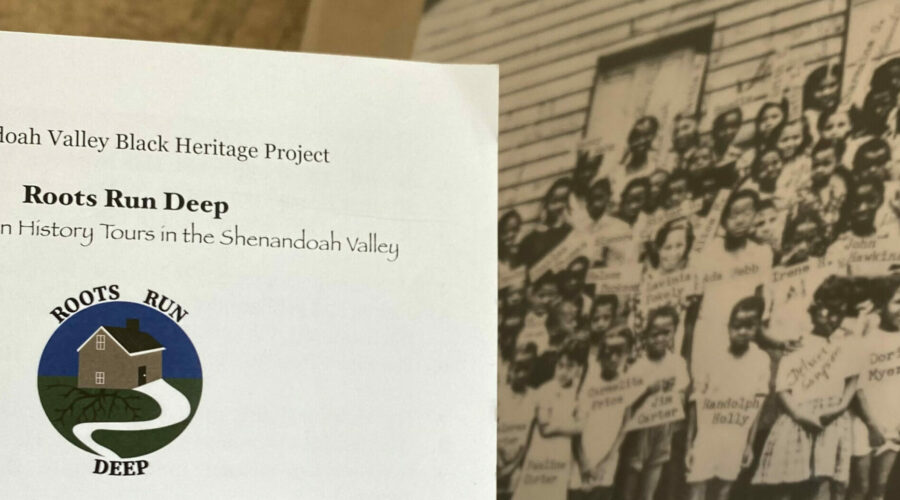 A brochure for the roots run deep tours in Harrisonburg, Virginia sits in front of an aged black and white photo of Black students gathered and posing for the photo outside of what appears to be a school building.