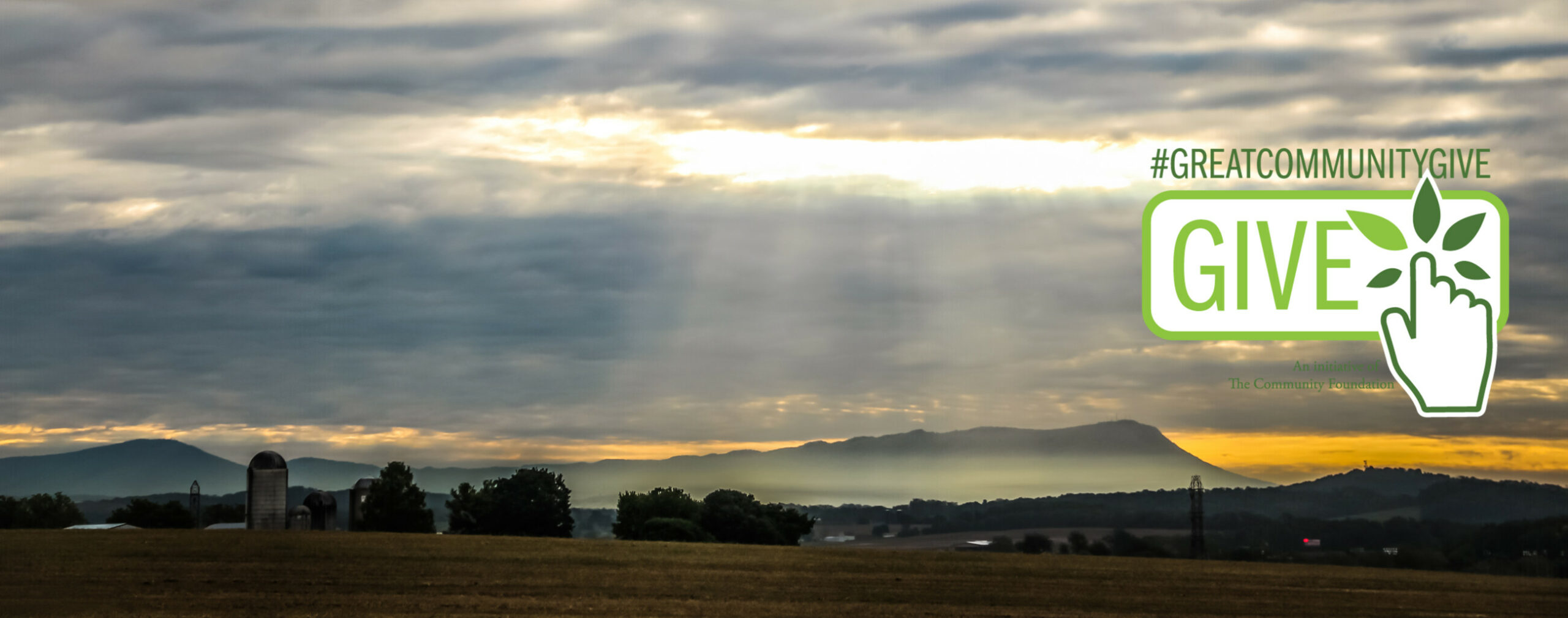 Sun shines through the clouds over the iconic Massanutten Mountain with farm fields in the foreground.