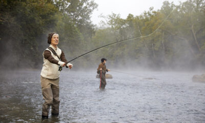 A Valley Treasure Award seal overlay a photo of a woman standing in what looks like a cold misty river casting a fly reel.