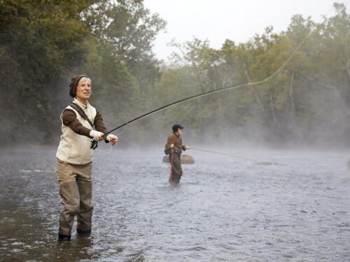 A Valley Treasure Award seal overlay a photo of a woman standing in what looks like a cold misty river casting a fly reel.